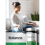 A young woman meditates on a sofa next to a bottle of Horbäach Chamomile, promoting relaxation.
