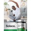 A young adult male stretches on a yoga mat and smiles, next to a bottle of Horbaach White Willow Bark.