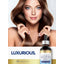 Young woman holds her long brown hair with a Carlyle Biotin bottle in her hand.