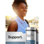 Young African American woman smiling in sunlight with a Horbaach Magnesium Citrate bottle outdoors.