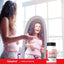 Young adult female smiles while measuring her waist in the mirror next to an AMPK Activator bottle.