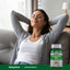 A young woman relaxes on a couch next to a bottle of Ashwagandha Root, capturing a serene lifestyle moment.