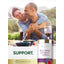 Middle-aged couple smiling and hugging outdoors at a table with food and a Carlyle Red Wine Extract bottle.