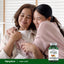 Two Asian women smiling and hugging, holding a bottle of Camu Camu Extract.