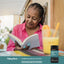 An older woman reading a book next to a CogniPeak Brain Support supplement bottle.