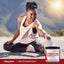 Young woman sitting outdoors, stretching her leg next to a container of Creatine Monohydrate.