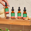 Adult's hand holding a Fungies Lion's Mane Mushroom Liquid Drops bottle with various flavors displayed on a wooden shelf.