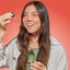 Young woman smiling while holding Fungies Lion's Mane Mushroom Liquid Drops bottle and a dropper.