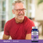 An older man smiles next to a bottle of Grape Seed Extract.