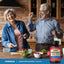 Senior couple laughing while cooking in a kitchen with a Lemon Bioflavonoid Complex bottle visible.