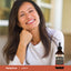 Woman smiling with her hand under her chin, next to a Lugol's Solution bottle.