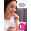 Young woman smiling, holding a capsule and a glass of water, with Keratin Hair Volumizer product in view.