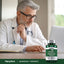 A middle-aged man in a doctor's coat uses a laptop next to a Magnesium L-Threonate bottle.
