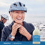 Senior woman adjusts bike helmet next to an older man, with a large bottle of Magnesium Oil beside them.