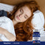 A young woman sleeps in bed holding a bottle of Melatonin.