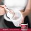 A woman prepares a drink by adding Multi Collagen Protein powder to a shaker cup.