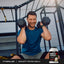 Middle-aged man smiling while holding dumbbells, with a MuscleFit Protein Vanilla tub placed beside him.