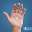 A yellow softgel capsule in a hand next to a scale showing it measures 1 inch (2.54 cm).