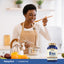 Lifestyle image of adult cooking in kitchen with Piping Rock Vitamin B100 B-Complex supplement bottle nearby