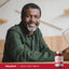 Adult smiling while seated indoors, with a Piping Rock Mega Q-Sorb® CoQ-10 200 mg with Black Pepper bottle nearby