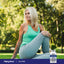 A senior woman stretches outdoors on grass next to a Calcium supplement bottle.