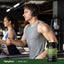 Lifestyle image of two adults exercising on treadmills at a gym with a Piping Rock Royal Jelly 2500 mg supplement bottle displayed in the bottom right corner
