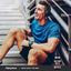 Young adult male in workout clothes sits on stairs, smiling, with a Mega Multi for Men bottle in the foreground.