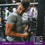 A man exercises in a gym with a tub of L-Glutamine Powder nearby.