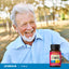 Lifestyle image of smiling older adult outdoors with Lindberg E-400 IU supplement bottle nearby