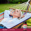 Lifestyle image of an adult relaxing in a hammock outdoors with a Lindberg L-Tryptophan 500 mg supplement bottle displayed in the bottom right corner