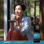 Adult sitting by a window holding a mug with Piping Rock Ultra Omega 3 + D3 Fish Oil supplement bottle nearby