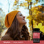 Adult smiling outdoors while wearing a knit hat, with a Piping Rock Vaginal Probiotic Flora Balance bottle nearby