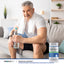Adult man seated on a sofa holding a bottle of water with Advanced Prostafit Prostate Support supplement bottle nearby