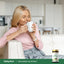 Adult woman relaxes on a couch, enjoying a mug aroma next to a Green Tea bottle.