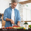 A middle-aged man chops tomatoes in a kitchen, with a bottle of Sunflower Lecithin nearby.