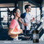 Adult woman and adult man running on treadmills at a gym with Piping Rock Chelated Multi Minerals Full Spectrum bottle displayed in the foreground.