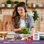A young woman making a salad next to a bottle of Probiotic Acidophilus.