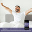 A man in his 30s or 40s stretches in bed, smiling beside a bottle of Sleep-3 Melatonin Gummies.