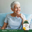 A senior woman smiles while glancing away, standing next to a Sunflower Lecithin bottle.