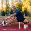 Middle-aged man stretches on a running track near a Supreme Stress B bottle, highlighting an active lifestyle.