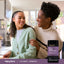 A mother and her teenage daughter smiling together in a kitchen with a bottle of Teen Multi + Probiotics.
