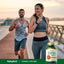 A young adult man and woman jogging outdoors with a Turmeric Curcumin bottle nearby.