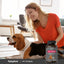 A woman pets a beagle while holding a bottle of Pet Vitamins.