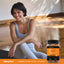 A woman smiling while sitting on a yoga mat next to a bottle of Vitamin C Gummy Slices.